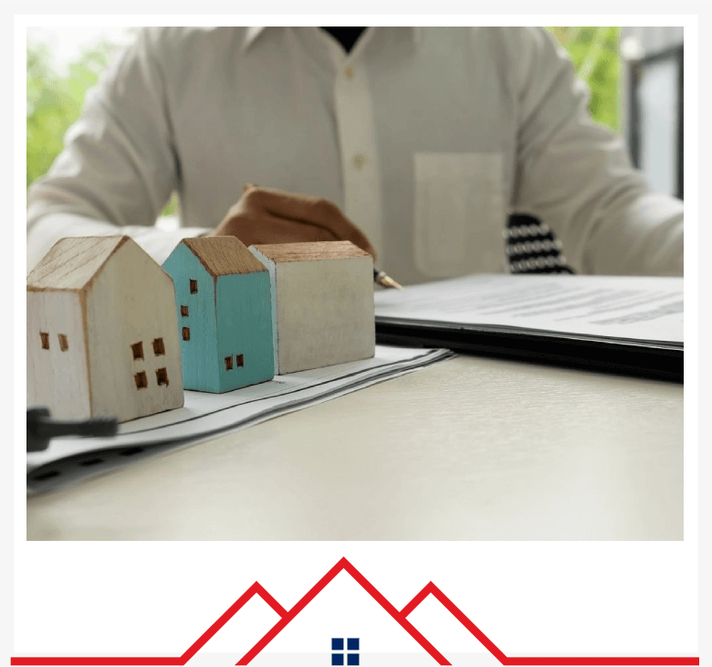 A man signing papers with model houses in front.